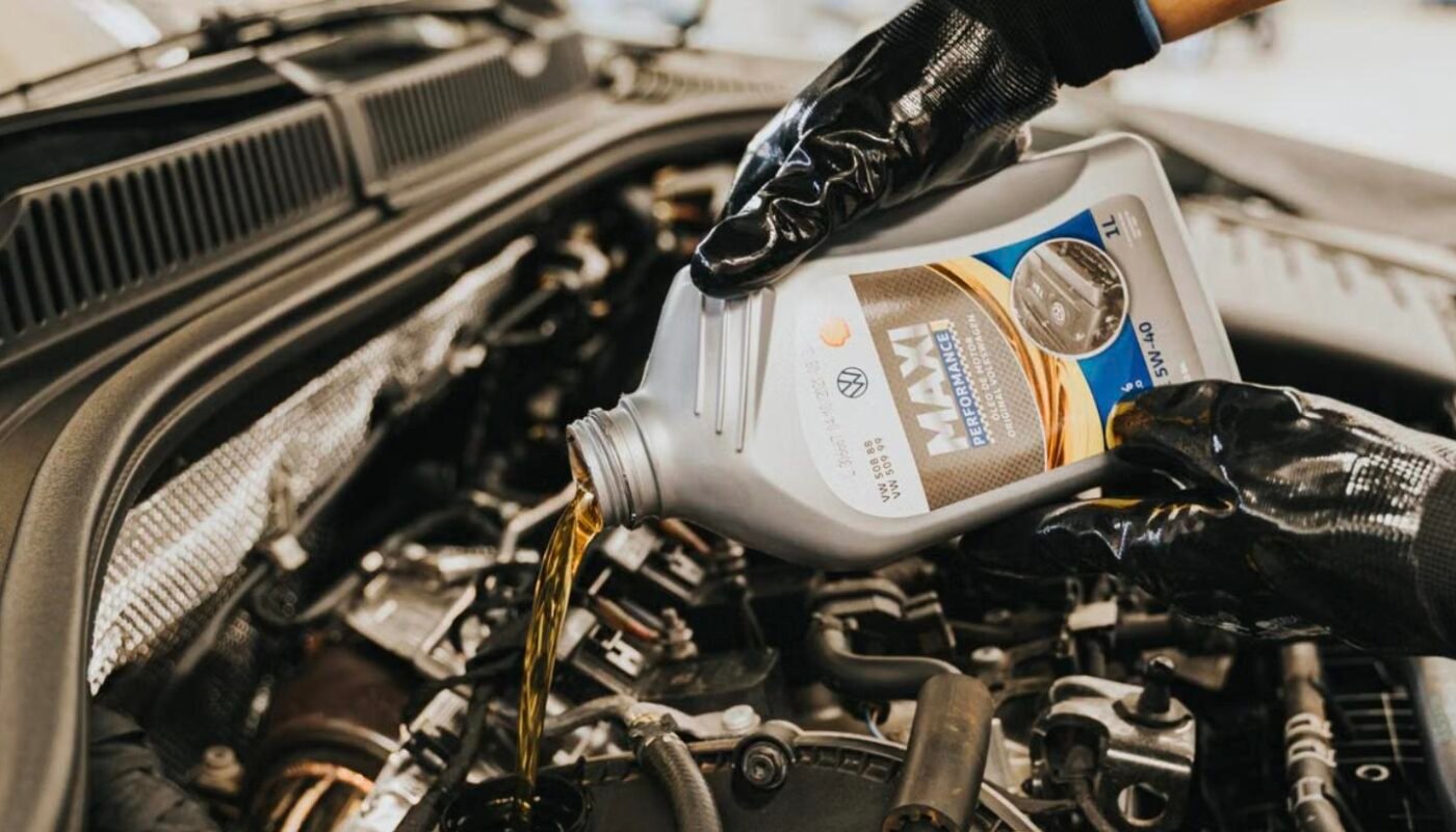 Mechanic pouring fresh engine oil into a diesel van engine to diagnose oil consumption
