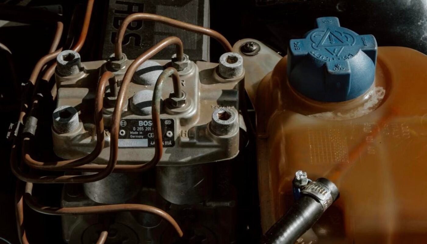 Close-up of a van coolant expansion tank and hose, checked while tracing a hidden coolant loss