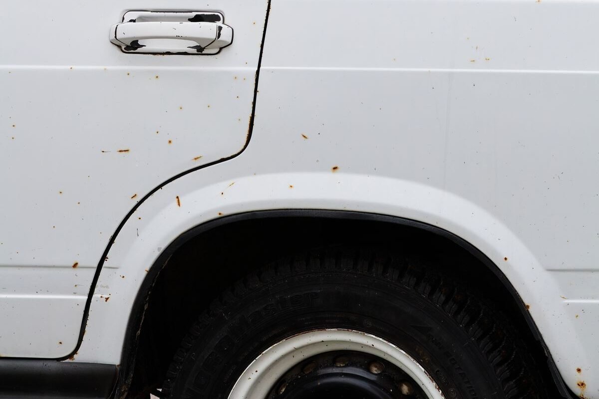 Close-up of rust spots on a vehicle wheel arch and side panel