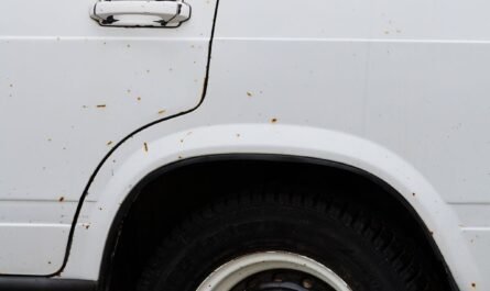 Close-up of rust spots on a vehicle wheel arch and side panel