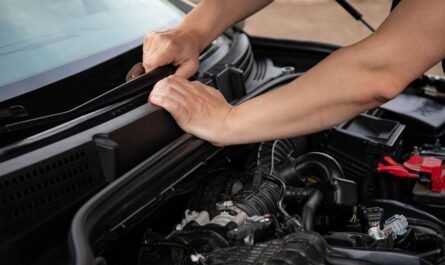 Hands repairing a van engine outdoors