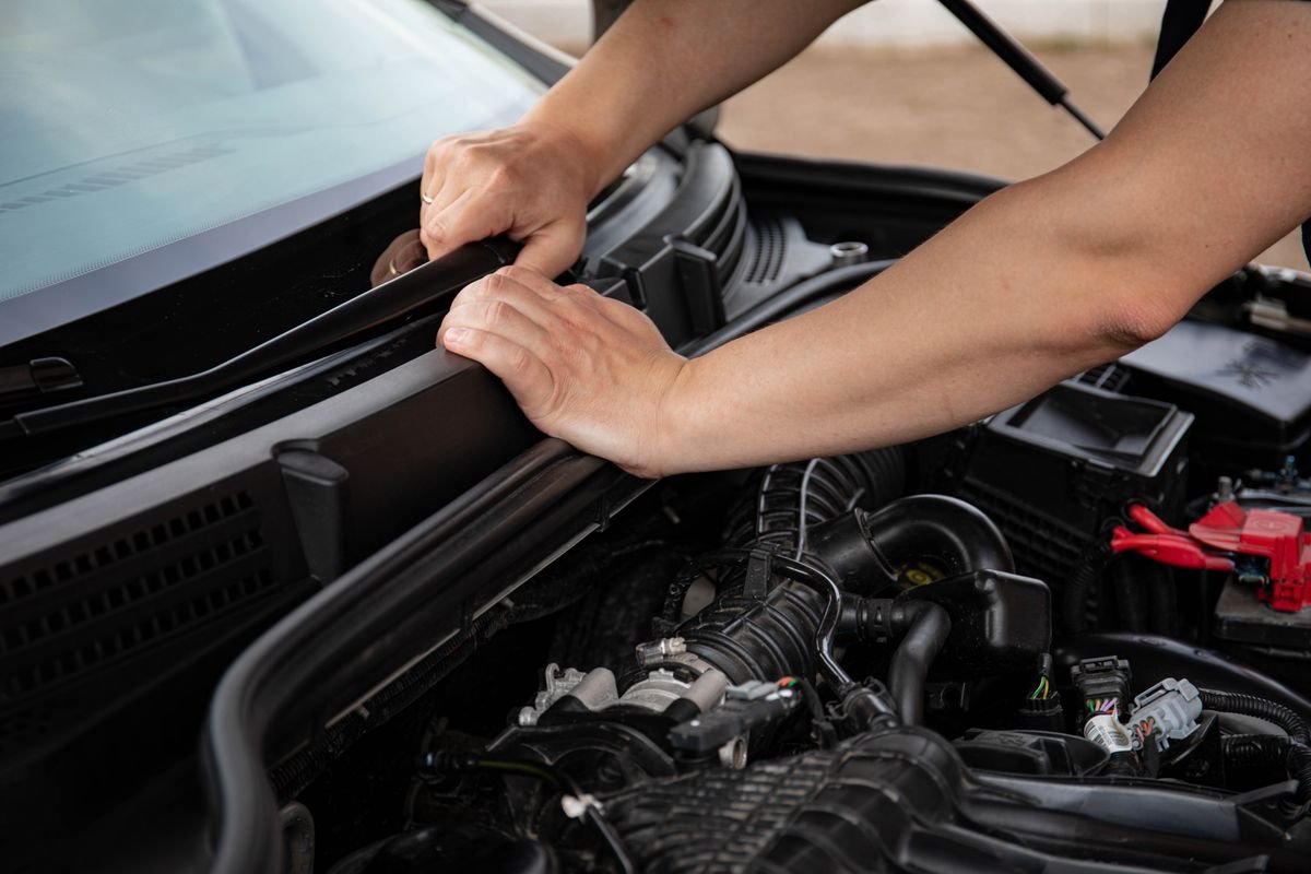Hands repairing a van engine outdoors
