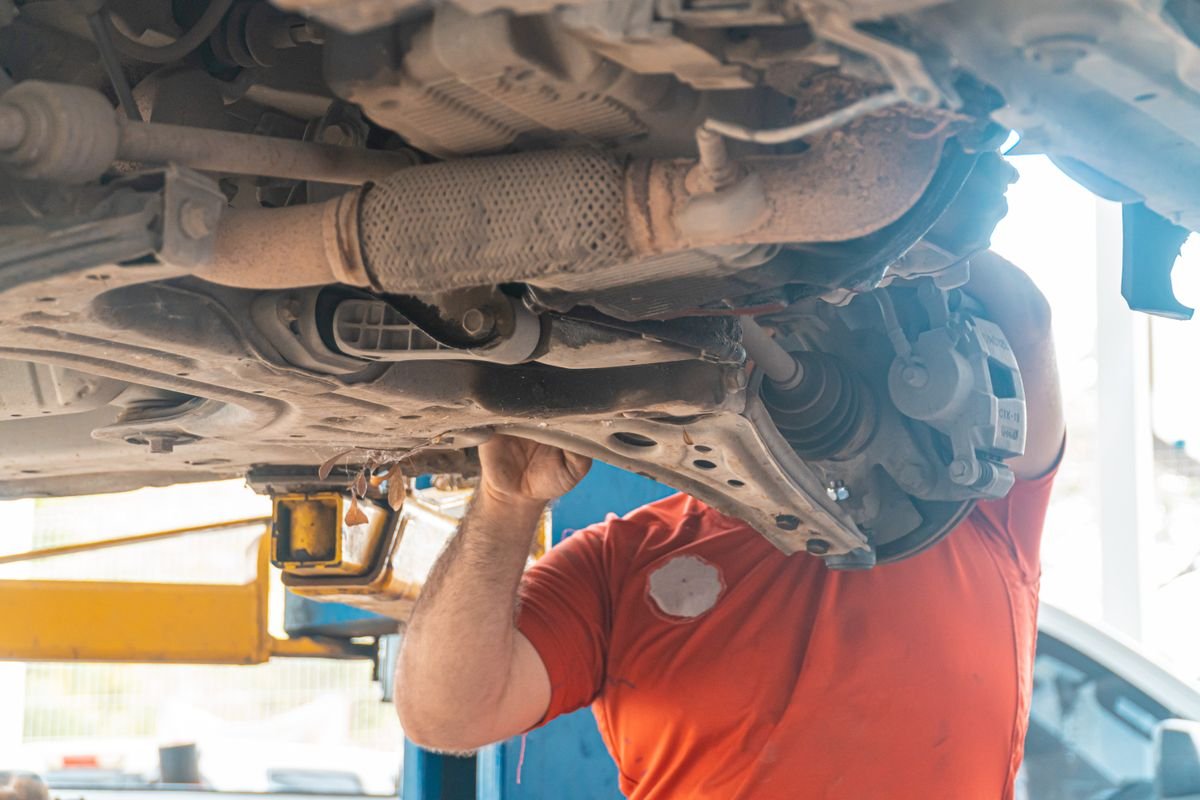 Mechanic inspecting the underside of a van for exhaust sensor faults