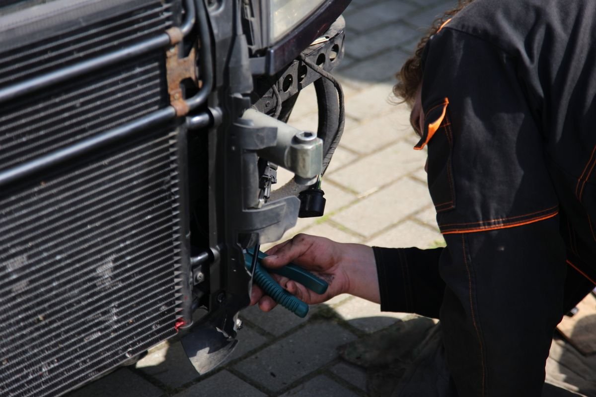 Mechanic working on a vehicle radiator and cooling fan area