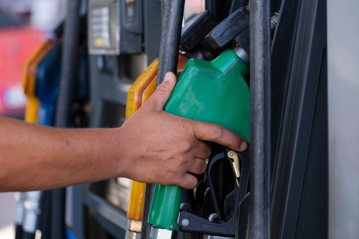 Hand holding a fuel nozzle while refuelling a vehicle
