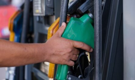 Hand holding a fuel nozzle while refuelling a vehicle